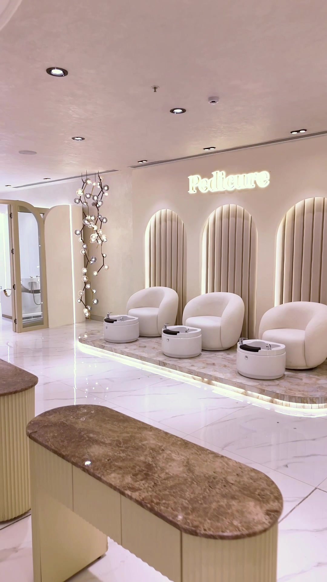 Sculptural pedicure chairs and soft, neutral finishes continue the salon’s visual language.